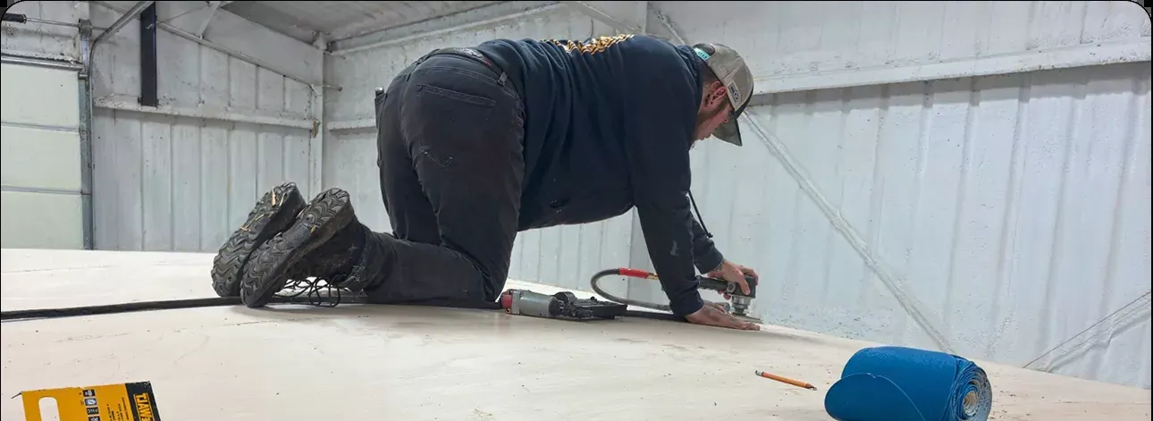 A technician preparing a roof surface by hand before coating